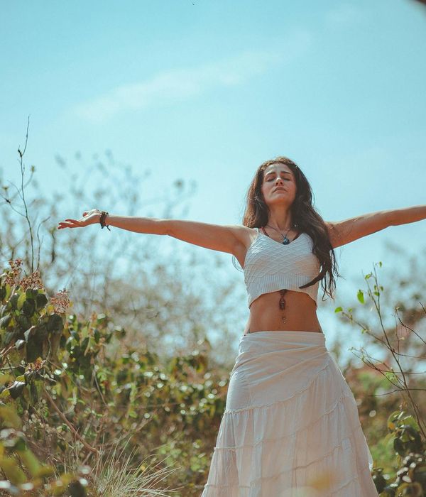 Woman performing a gentle stretching yoga pose in a calm, dark environment.